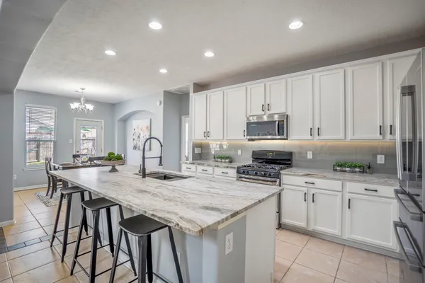 a kitchen with granite countertop white cabinets and stainless steel appliances