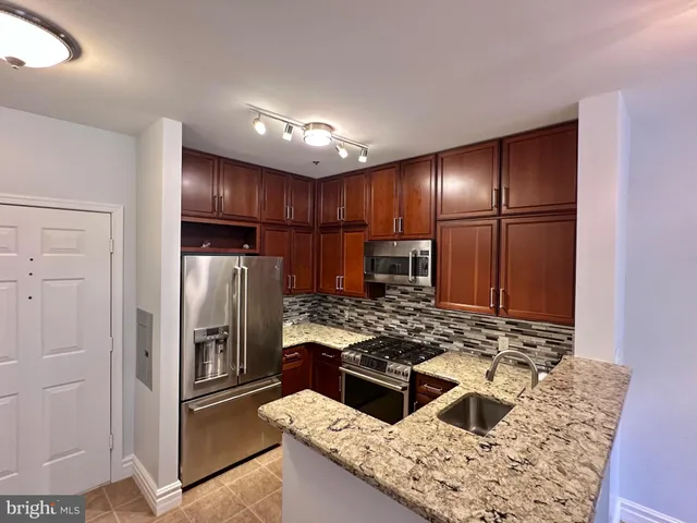 a kitchen with stainless steel appliances granite countertop a refrigerator and a stove