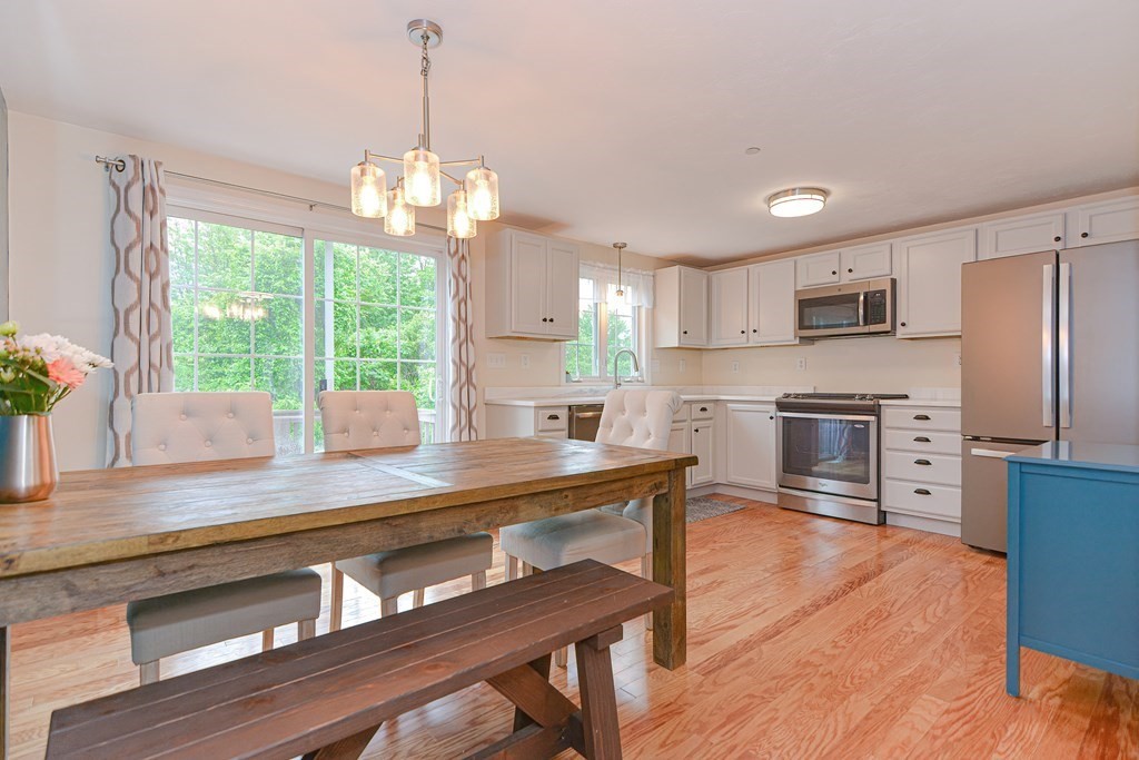 41 Boston Road, Unit 351 Billerica, MA 01862 - Photo 3 of 25 a kitchen with stainless steel appliances granite countertop a refrigerator a sink dishwasher a stove and a dining table with wooden floor