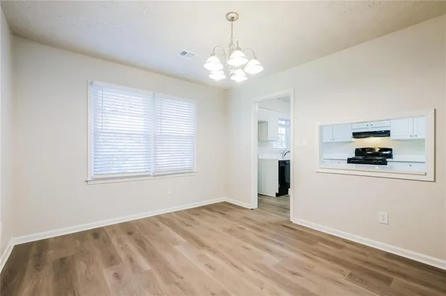a kitchen with granite countertop a stove a sink and white cabinets with wooden floor