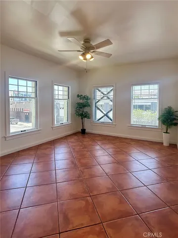 a view of an empty room with windows and chandelier fan