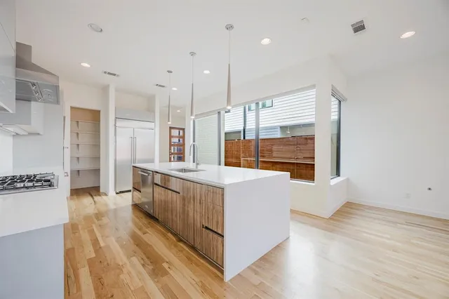 a large white kitchen with wooden floor and a large window
