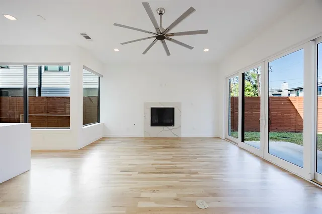 a view of empty room with wooden floor and fan