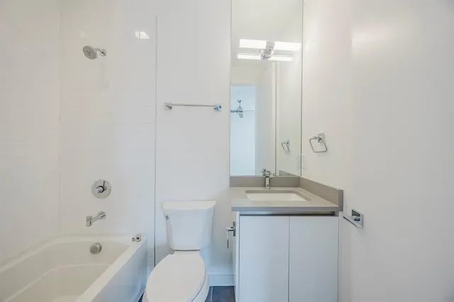 a bathroom with a granite countertop sink a toilet and shower