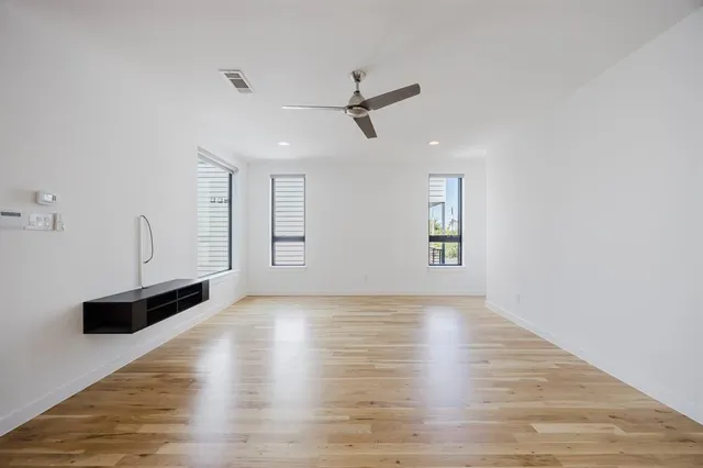 a view of an empty room with window and wooden floor