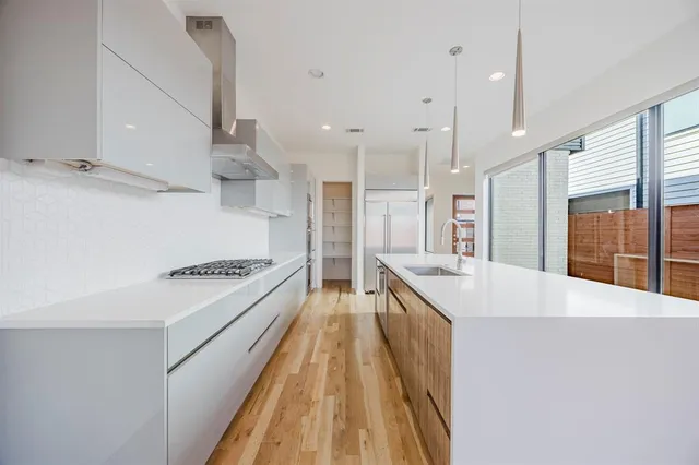a large kitchen with kitchen island a stove a sink a center island and wooden floor
