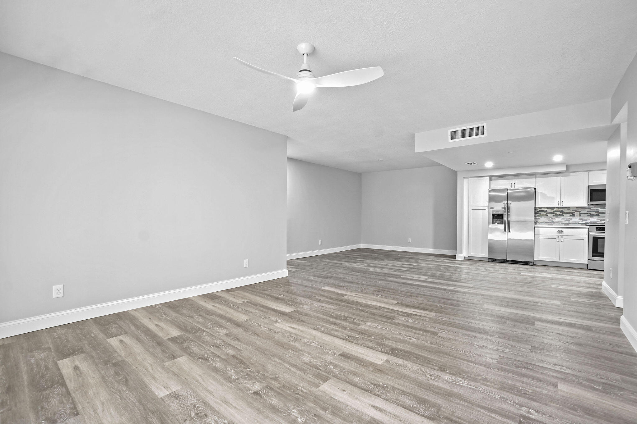 250 Southeast Four Winds Drive, Unit 204 Stuart, FL 34996 - Photo 4 of 32 a view of an empty room with wooden floor and a kitchen