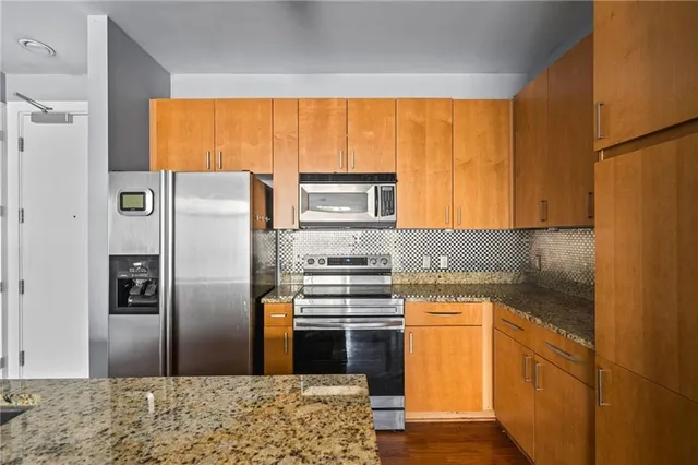a kitchen with stainless steel appliances granite countertop a refrigerator a stove and a sink with wooden floor