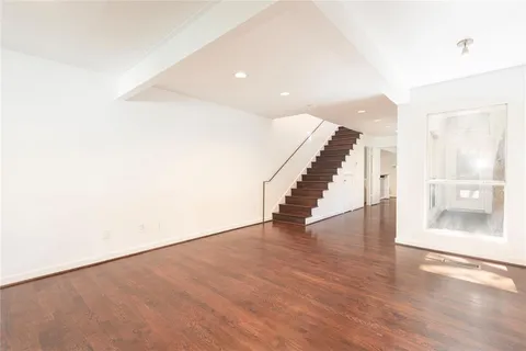 a view of an empty room with wooden floor and stairs