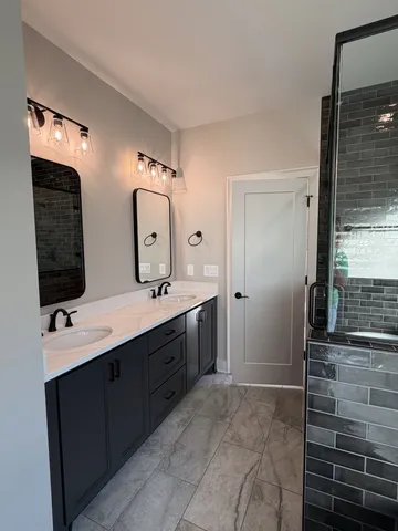a spacious bathroom with a double vanity sink a mirror and a shower