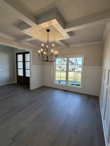 an empty room with wooden floor and chandelier