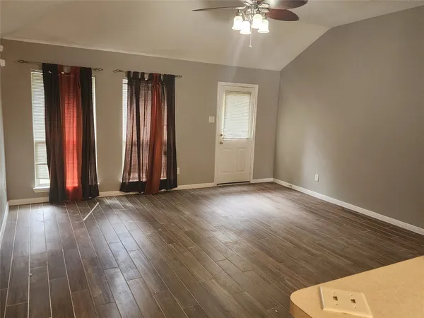 an empty room with wooden floor and windows
