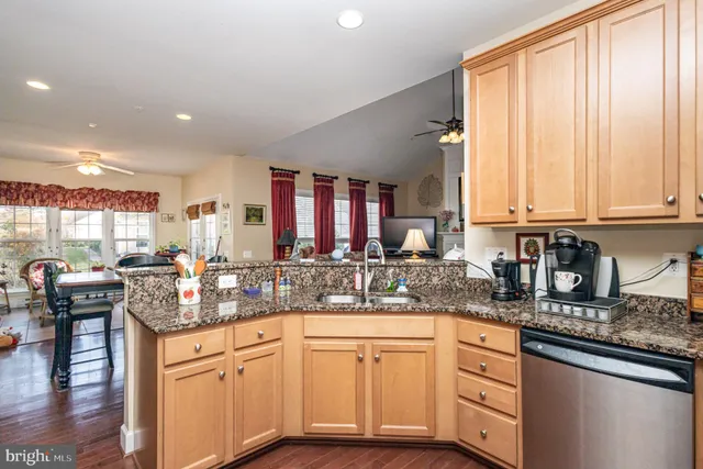 a kitchen with granite countertop a sink white cabinets and black stainless steel appliances