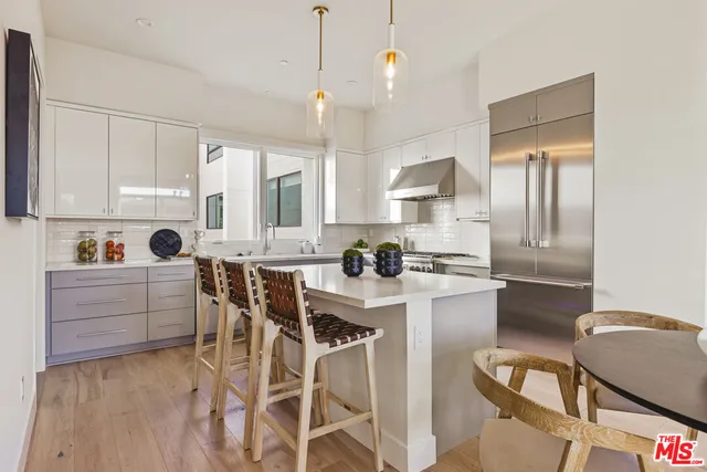 a kitchen with stainless steel appliances granite countertop a stove a refrigerator a sink a dining table and chairs with wooden floor