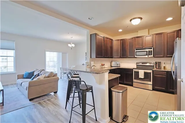 a kitchen with stainless steel appliances granite countertop a stove top oven a sink dishwasher a dining table and chairs with wooden floor