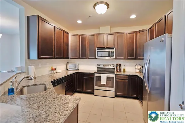 a kitchen with kitchen island granite countertop a sink stainless steel appliances and cabinets