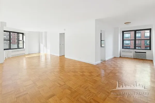 a view of an empty room with window and wooden floor