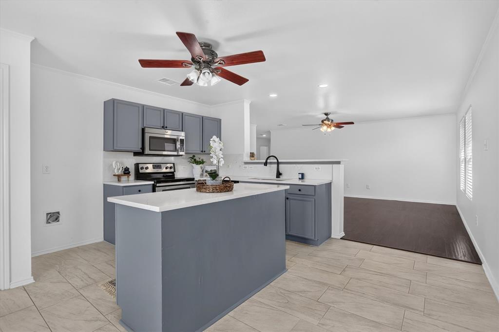 Kitchen featuring gray cabinetry, stainless steel appliances, a center island with a white countertop, and wood-finish tile flooring