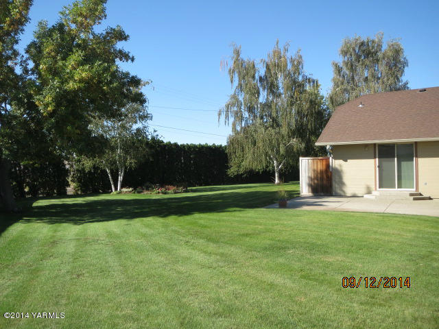 411 East Duffield Road Moxee, WA 98936 - Photo 3 of 19 a view of a white house in front of a big yard with plants and large trees