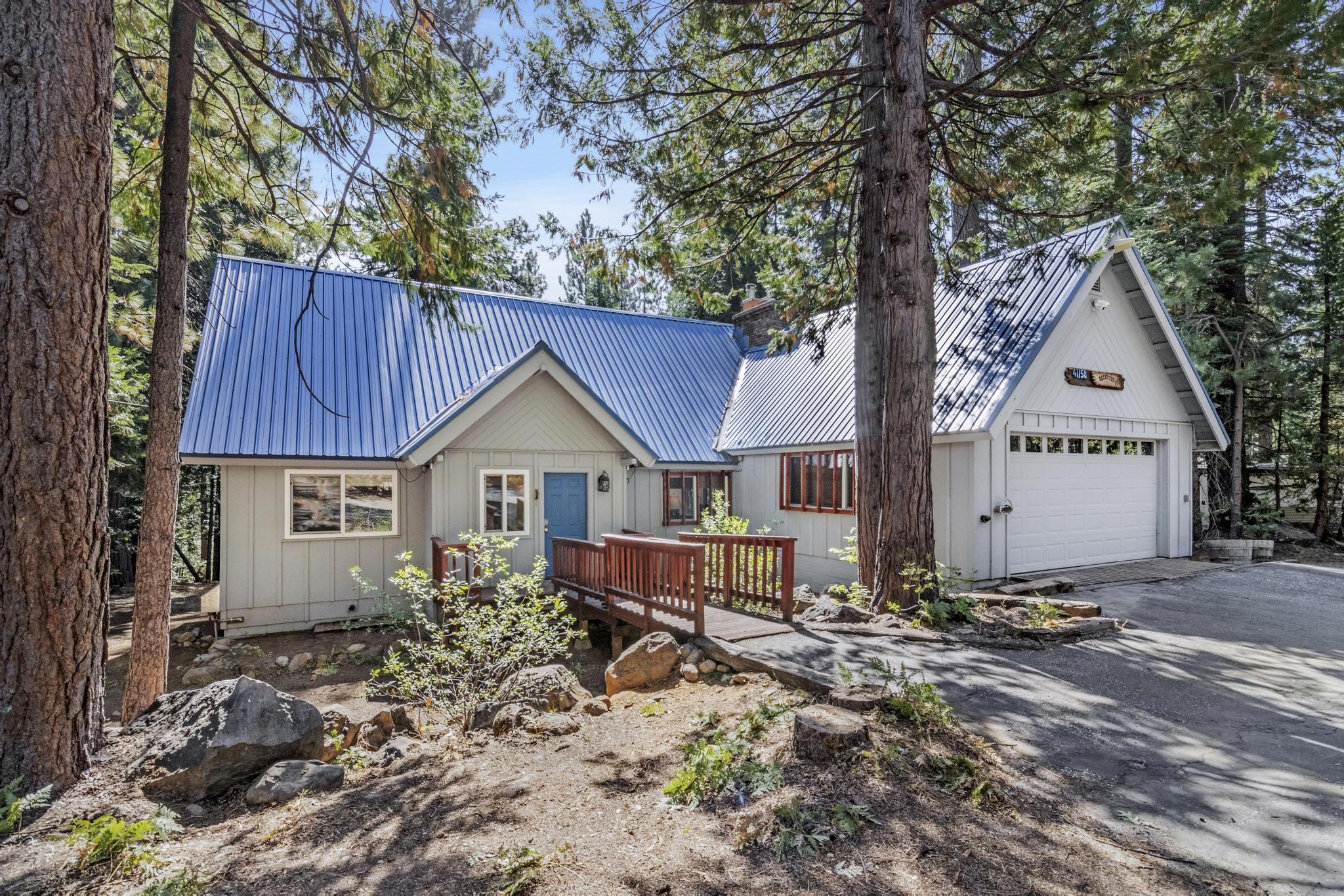 a view of a house with large trees and wooden fence