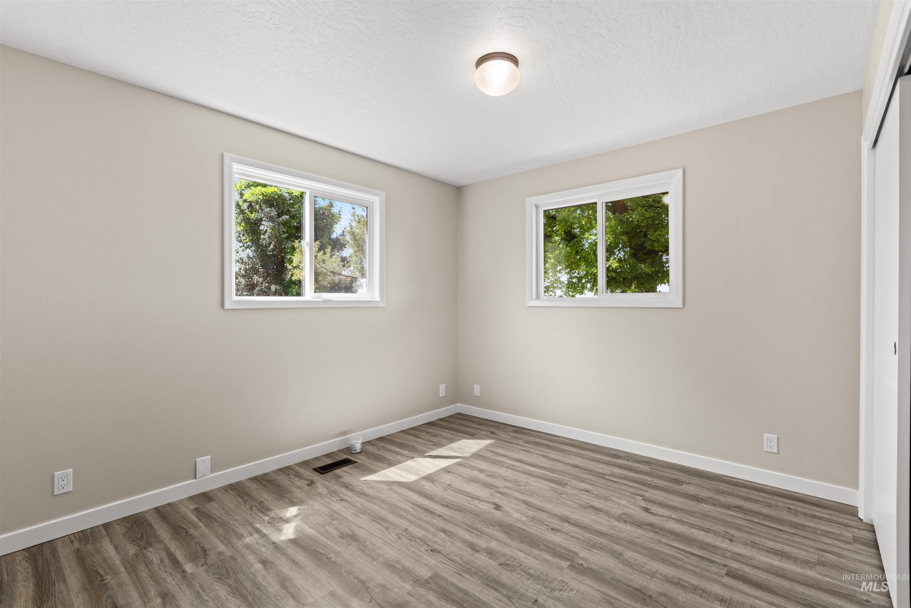 12184 Hill Road Payette, ID 83661 - Photo 23 of 35 Room featuring wood-finish flooring, two windows with white trim, and light neutral wall paint