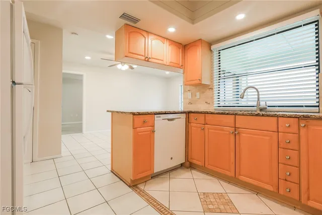 a view of a refrigerator in kitchen and an empty room in wooden floor