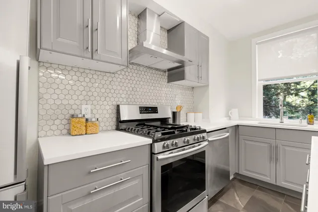 a kitchen with stainless steel appliances a stove a white cabinets and a sink