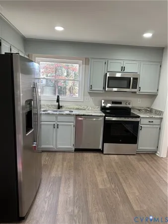 a kitchen with stainless steel appliances a stove a sink a refrigerator a microwave and cabinets