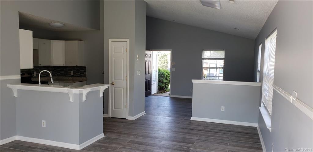 9610 Rau Court Charlotte, NC 28215 - Photo 3 of 10 a view of a kitchen and an empty room with wooden floor and a window