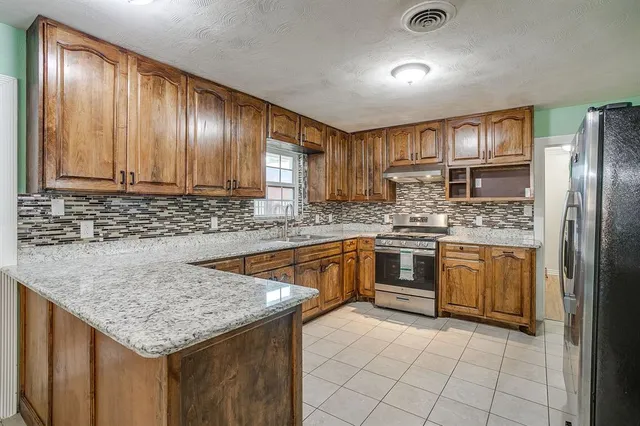 a kitchen with stainless steel appliances granite countertop a sink stove and refrigerator