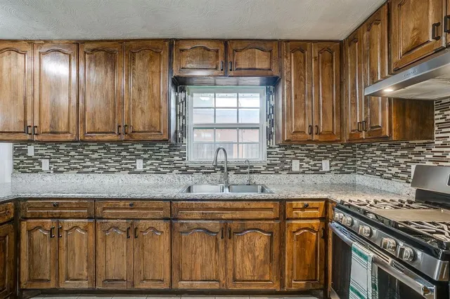 a kitchen with granite countertop a sink stove and cabinets