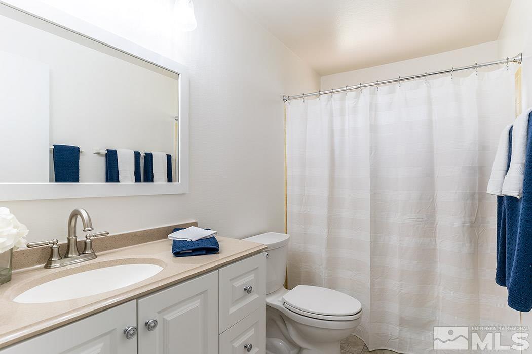 3685 Renee Way Reno, NV 89503 - Photo 17 of 26 a bathroom with a granite countertop sink a toilet and a mirror