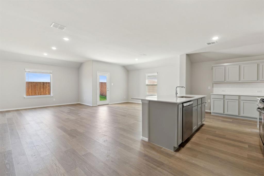 1122 Sunward Road Princeton, TX 75407 - Photo 35 of 36 a kitchen with stainless steel appliances wooden floors and white cabinets