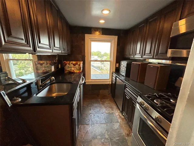 a kitchen with granite countertop a stove sink and refrigerator