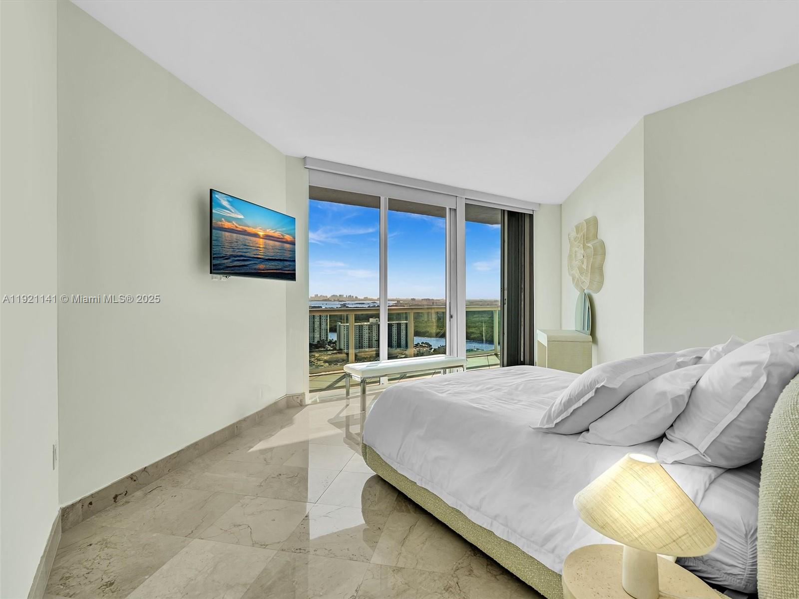 16500 Collins Avenue, Unit PH54 Sunny Isles Beach, FL 33160 - Photo 66 of 97 a spacious bedroom with a bed and a large window