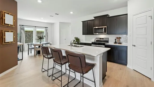 a kitchen with stainless steel appliances a table chairs refrigerator and microwave