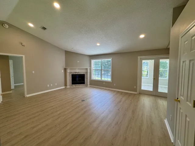an empty room with wooden floor and fireplace