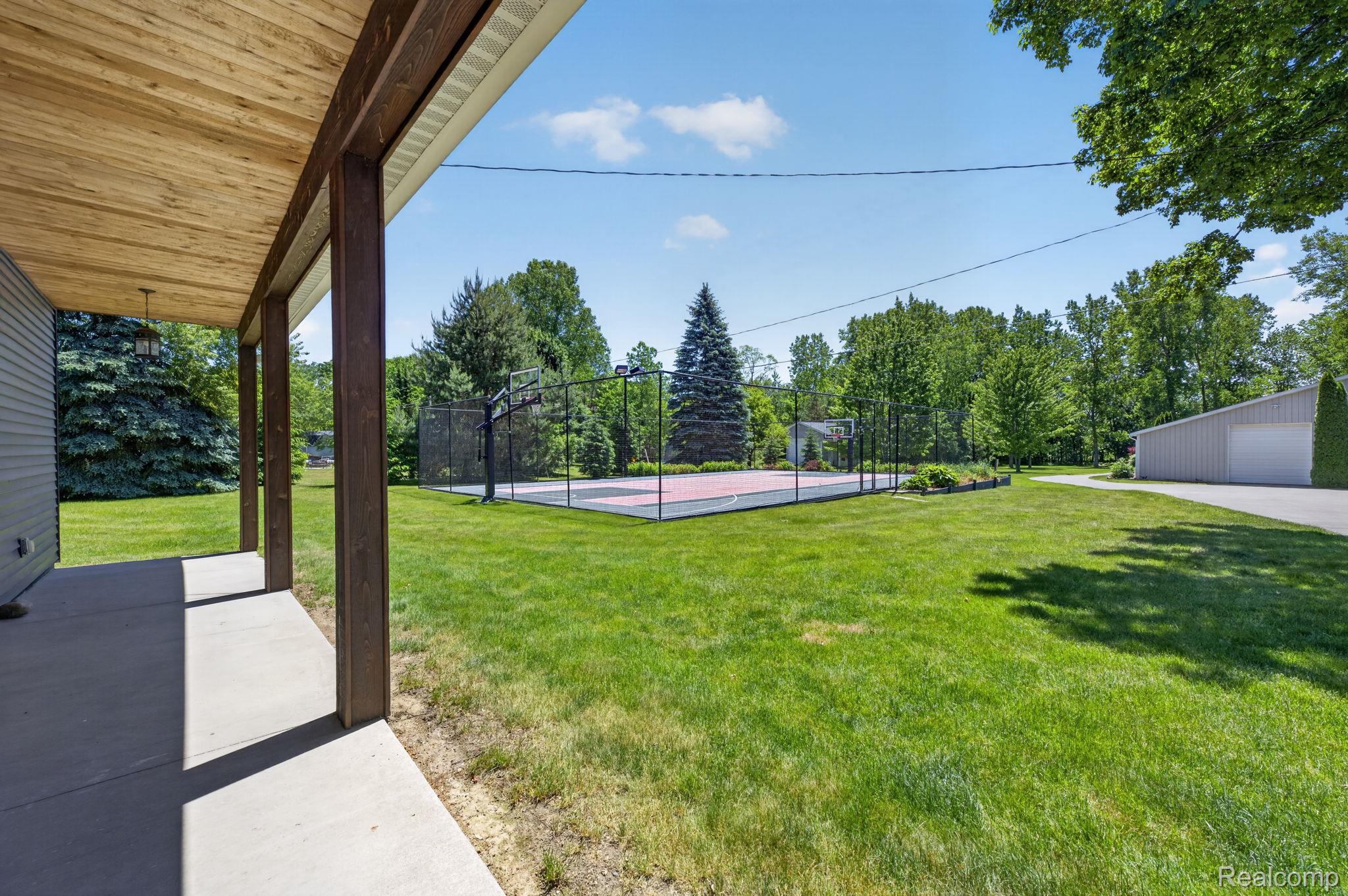 9353 Hill Road Swartz Creek, MI 48473 - Photo 68 of 98 Expansive green lawn with a dedicated sports court, bordered by mature trees
