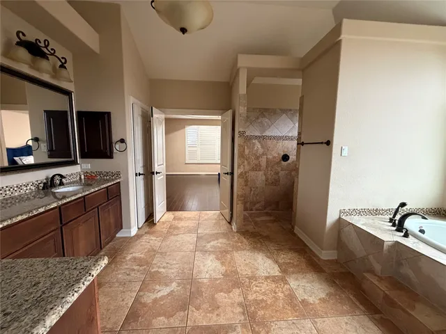 a large bathroom with a granite countertop tub sink shower and mirror