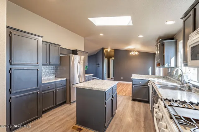 a kitchen with stainless steel appliances granite countertop a refrigerator a sink a stove and a refrigerator with wooden floor