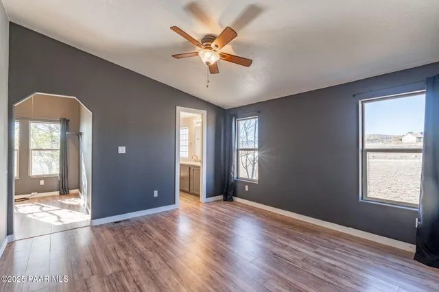 a view of an empty room with window and wooden floor