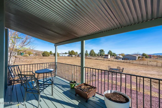a view of a balcony with wooden floor next to a yard