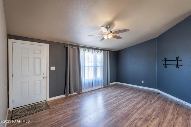 a view of empty room with wooden floor and fan