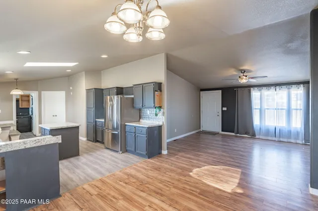 a open kitchen with stainless steel appliances granite countertop a refrigerator a stove a sink dishwasher and a dining table with wooden floor