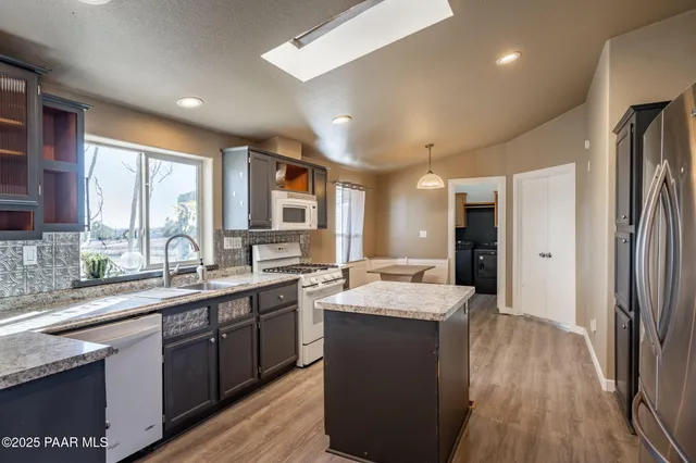 a large kitchen with stainless steel appliances kitchen island granite countertop a sink refrigerator and cabinets