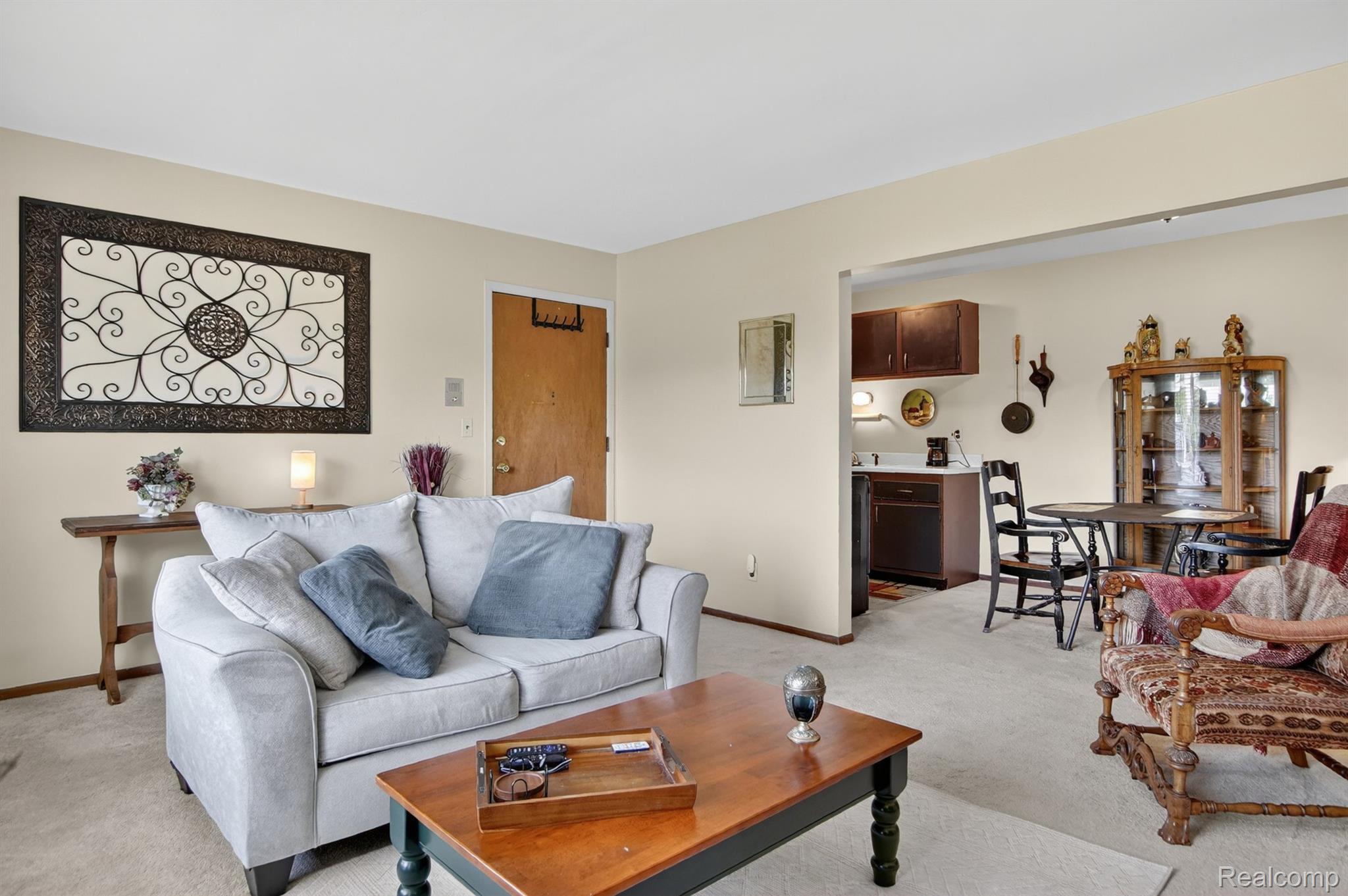 24111 Meridian Road, Unit 116 Grosse Ile, MI 48138 - Photo 9 of 26 Carpeted living space with a neutral color palette, featuring a broad entryway to the kitchen and dining area