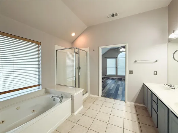 a bathroom with a granite countertop sink a mirror a bathtub and next to a window