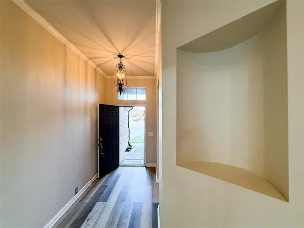 a view of a hallway with wooden floor and a chandelier