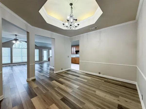 a view of an empty room with wooden floor and a chandelier