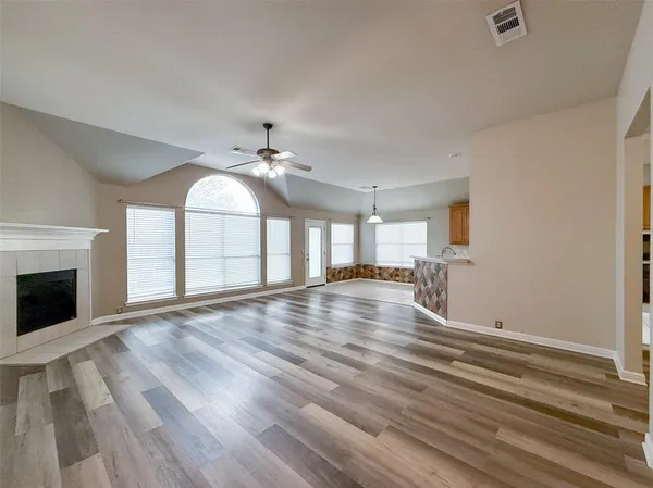 a view of empty room with wooden floor and fan
